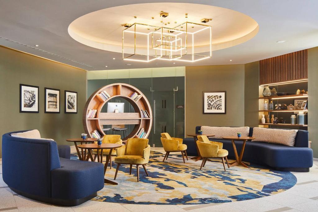 un hall avec des tables, des chaises et un lustre dans l'établissement London Marriott Hotel Kensington, à Londres