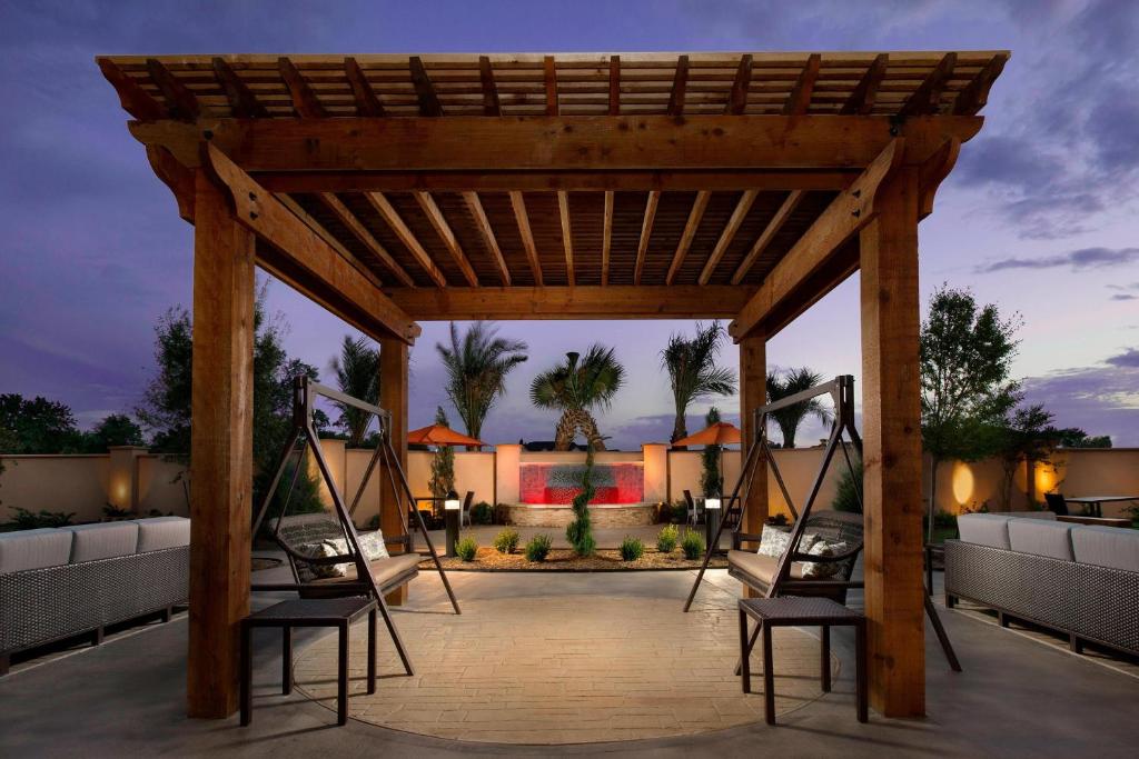 a wooden pergola with chairs on a patio at Courtyard Houston NW/290 Corridor in Houston