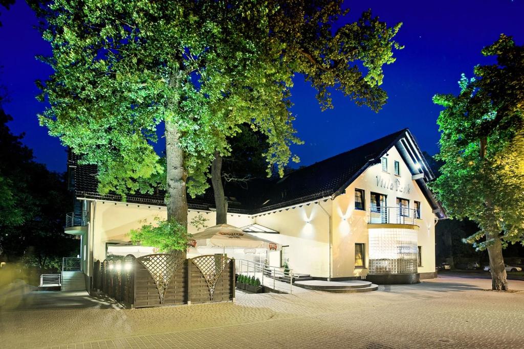 Una casa blanca con un árbol delante. en Villa Park, en Goleniów