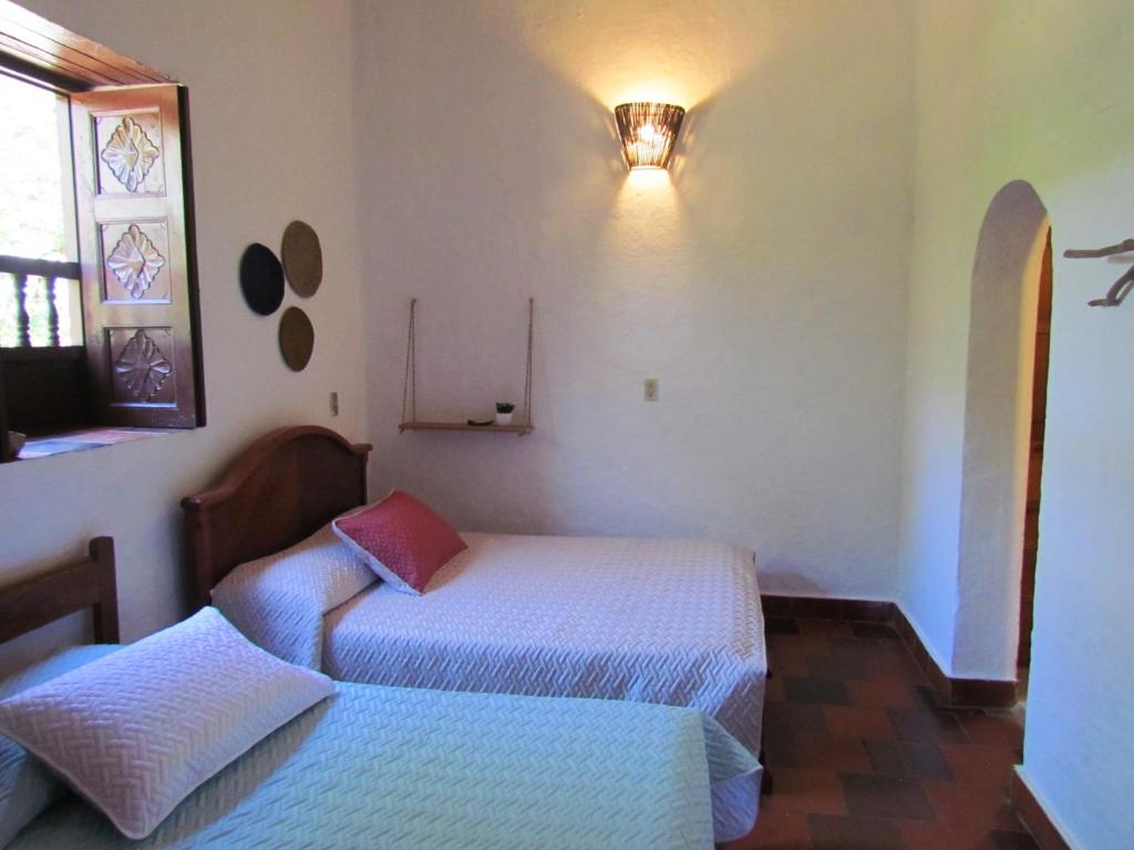 a bedroom with two beds and a window at Casa Yerbabuena- Rustiko in Barichara