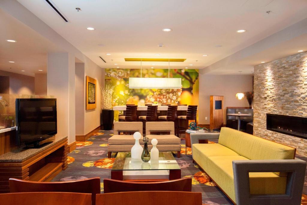 a living room with a yellow couch and a television at Courtyard by Marriott Ithaca Airport/University in Ithaca