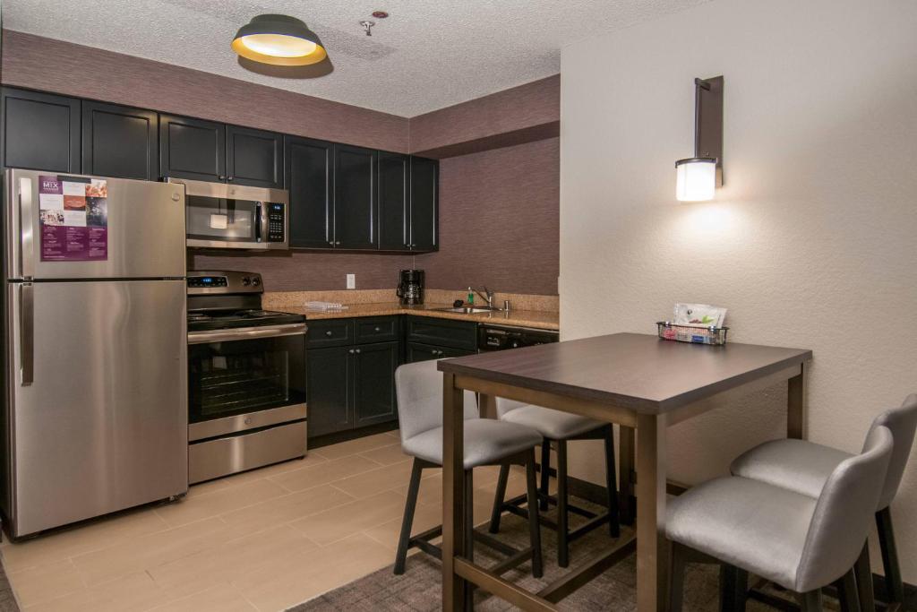 uma cozinha com uma mesa e um frigorífico de aço inoxidável em Residence Inn by Marriott Springdale em Springdale