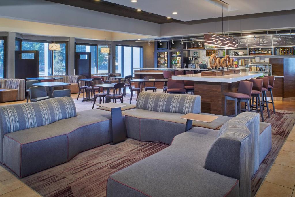 a restaurant with couches and tables and a bar at Courtyard by Marriott Detroit Warren in Warren