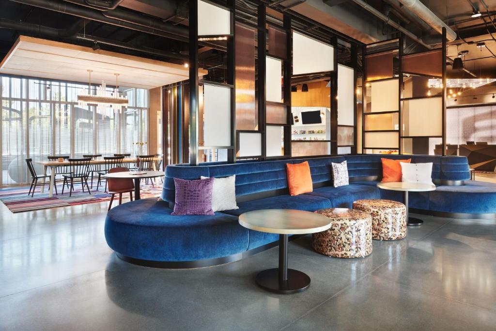 a lobby with a blue couch and tables at Aloft Atlanta Perimeter Center in Sandy Springs