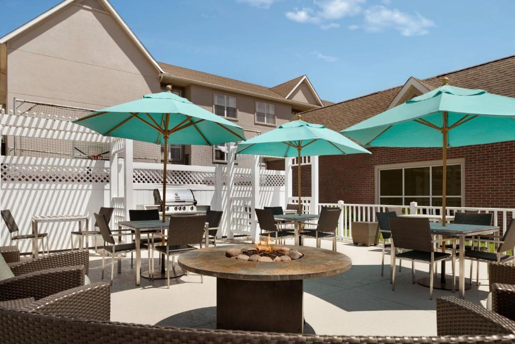 un patio con mesas, sillas y sombrillas en Residence Inn Canton en North Canton