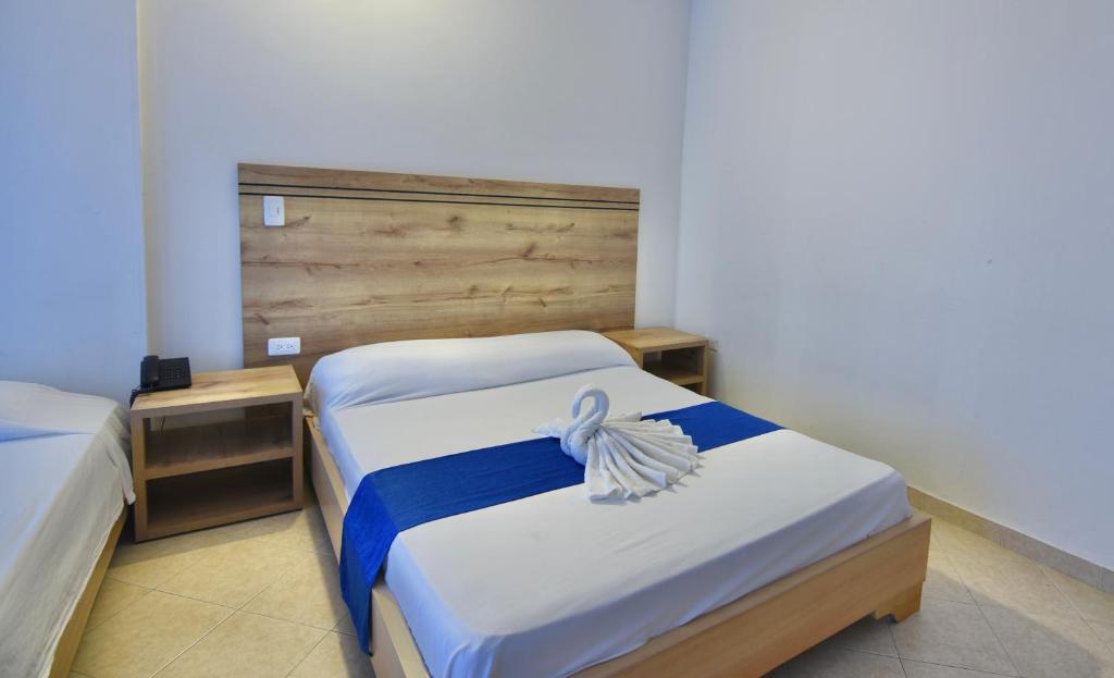 a bedroom with two beds and a wooden headboard at Hotel Comercial in Sincelejo