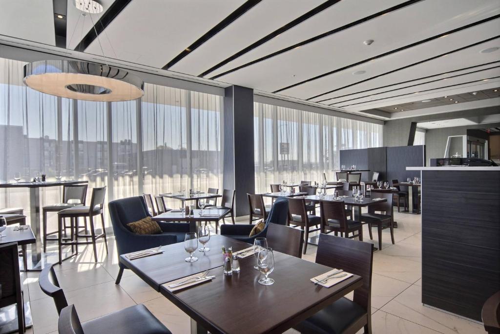 un restaurante con mesas, sillas y ventanas grandes en Courtyard by Marriott Quebec City, en Quebec