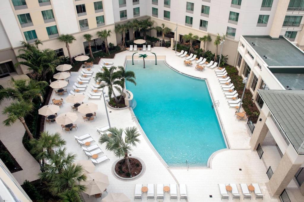 una vista aérea de una piscina del hotel con sillas y sombrillas en SpringHill Suites by Marriott Orlando Theme Parks/Lake Buena Vista, en Orlando