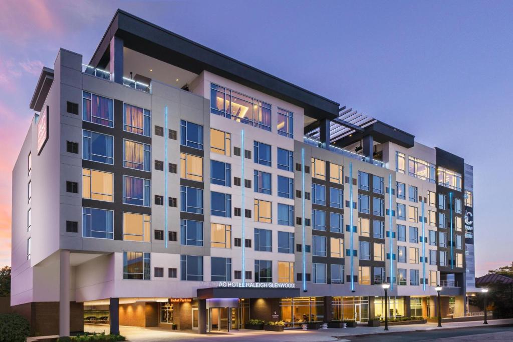 a large white building with many windows at dusk at AC Hotel By Marriott Raleigh Downtown in Raleigh