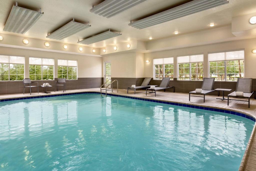 Residence Inn Houston Northwest / Willowbrook في هيوستن: مسبح في غرفة الفندق مع الكراسي والطاولات