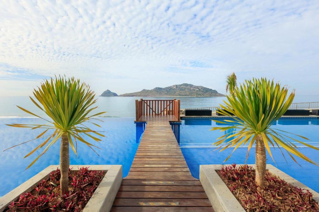 a dock with two palm trees in front of the water at Courtyard by Marriott Mazatlan Beach Resort in Mazatlán