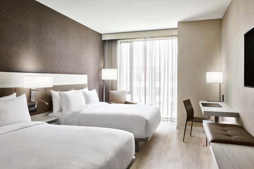 a hotel room with two beds and a desk at AC Hotel By Marriott Dallas By The Galleria in Dallas