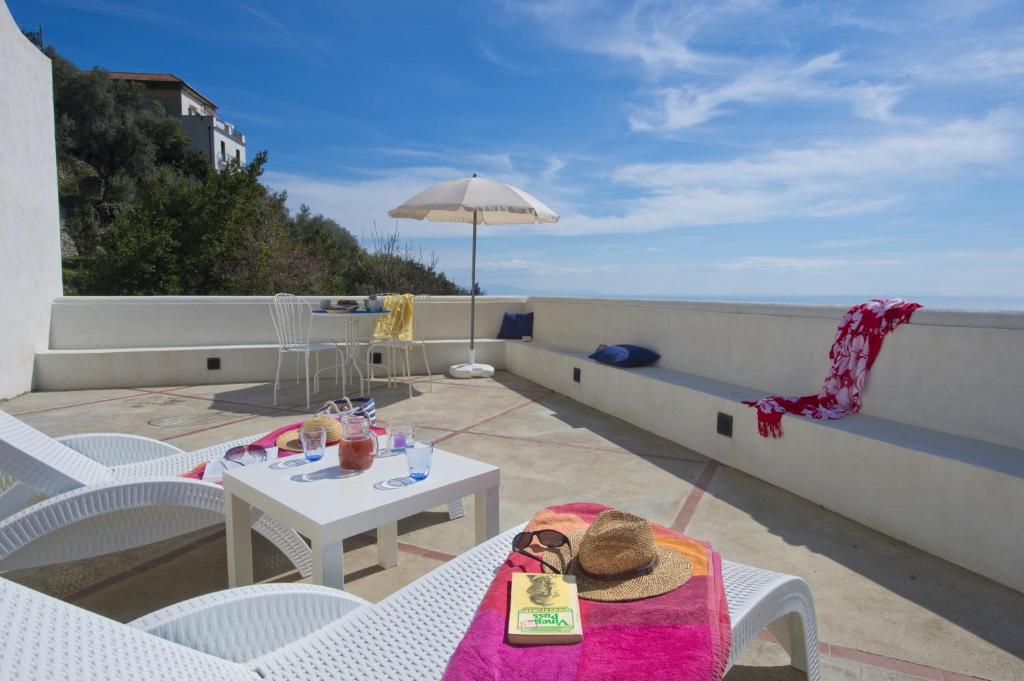 a balcony with a table and chairs and an umbrella at La Scivitella in Amalfi