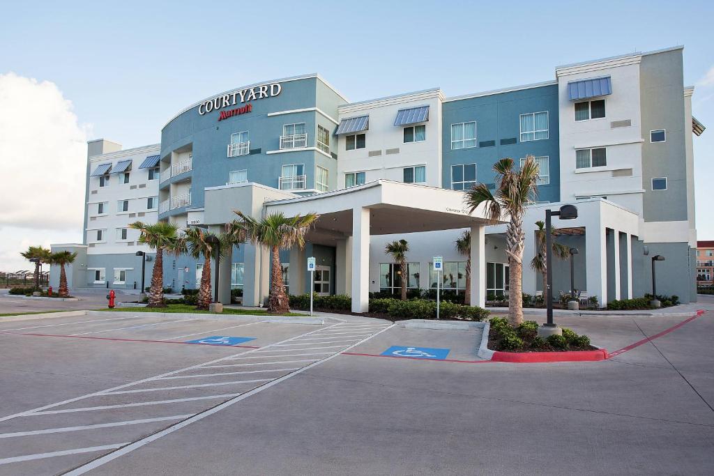 un gran edificio con palmeras en un aparcamiento en Courtyard by Marriott Galveston Island, en Galveston