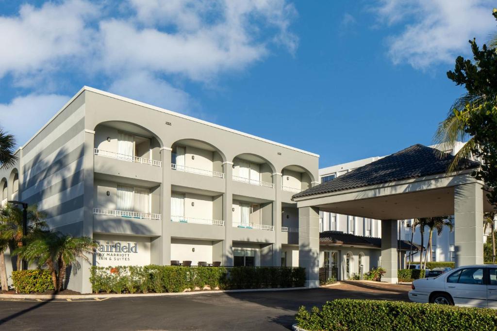 Fairfield Inn and Suites by Marriott Palm Beach في بالم بيتش: مبنى أبيض فيه سيارة متوقفة أمامه