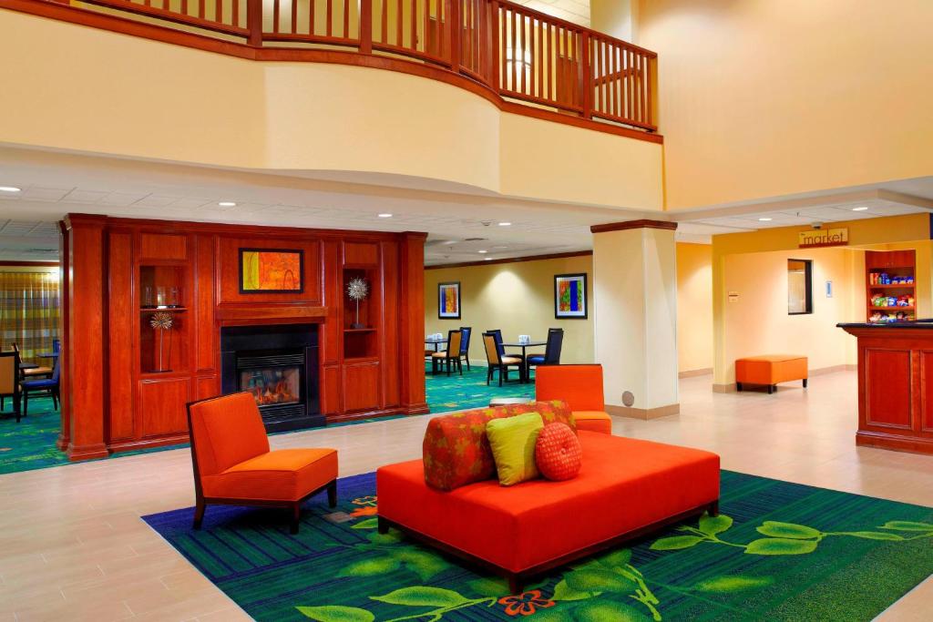 a lobby with a red couch and chairs and a fireplace at Fairfield Inn & Suites Phoenix Midtown in Phoenix