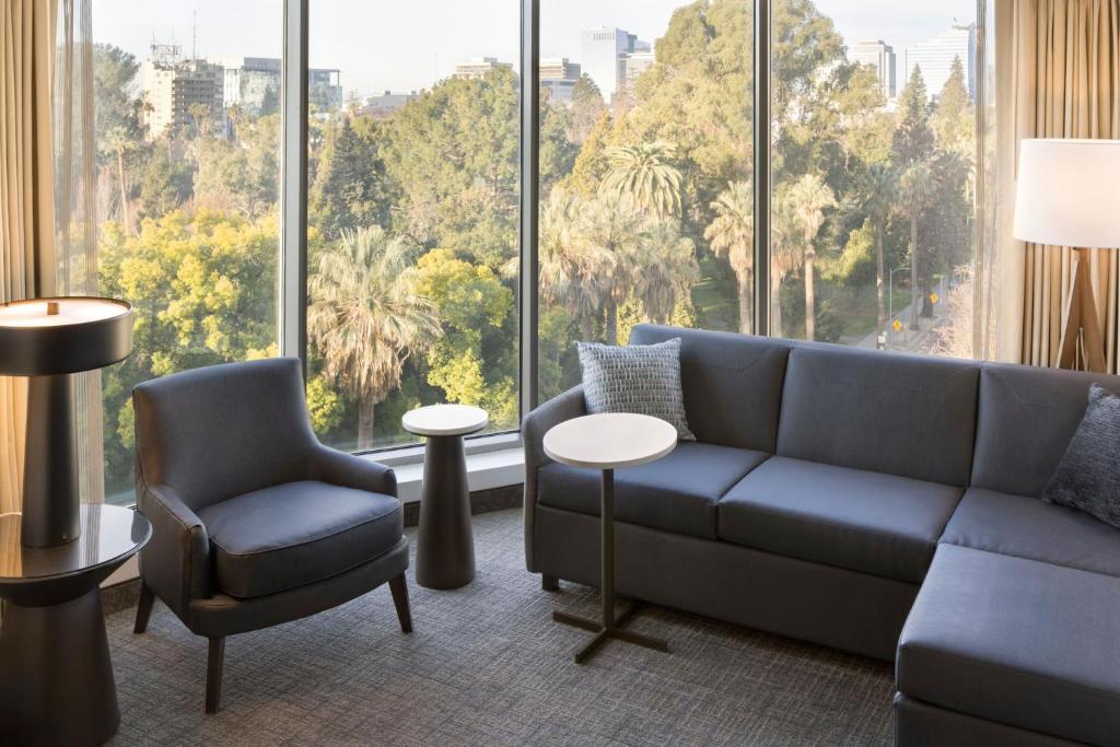 - un salon avec un canapé, des chaises et une grande fenêtre dans l'établissement Residence Inn by Marriott Sacramento Downtown at Capitol Park, à Sacramento