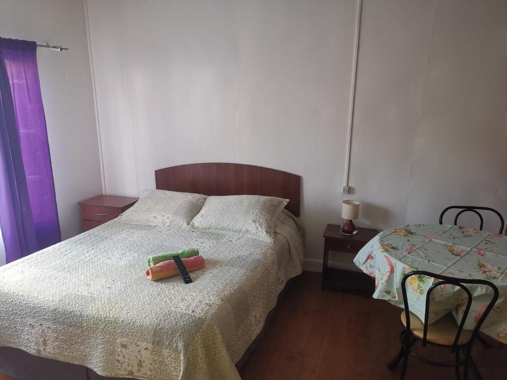 a small bedroom with a bed and a table at Hostal y Cabañas Maribel Zuñiga in Valdivia