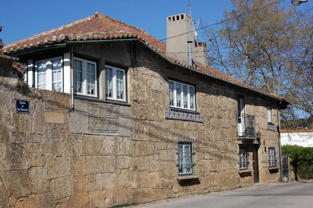 an old stone building with white windows on a street at Casa da Quinta De S. Martinho in Vila Real