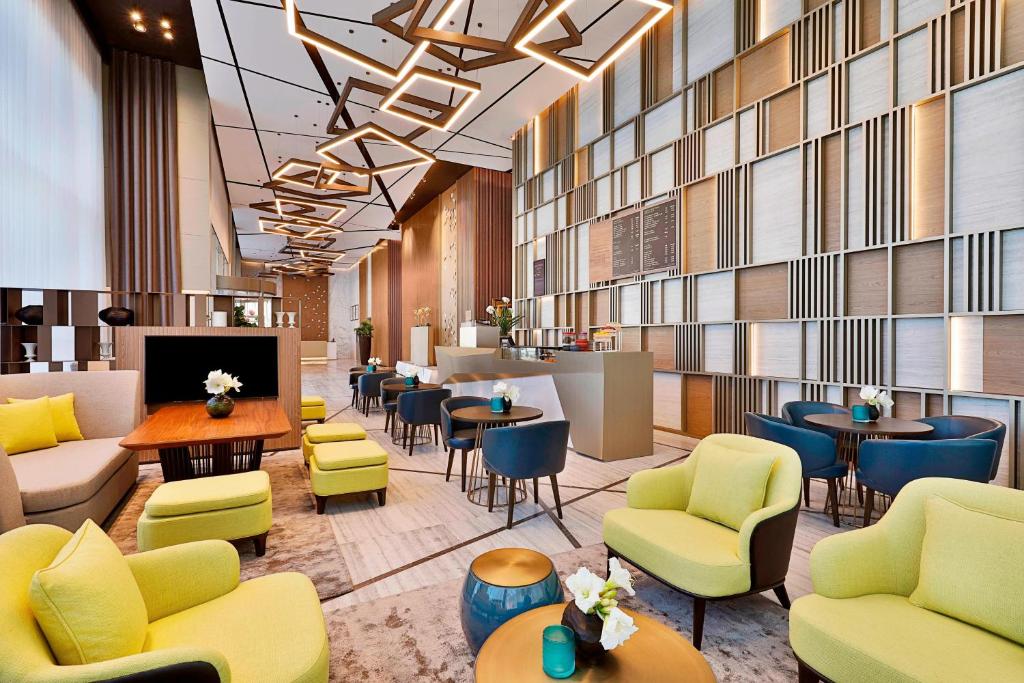 un vestíbulo con sofás, mesas y sillas en Courtyard by Marriott Dubai, Al Barsha, en Dubái