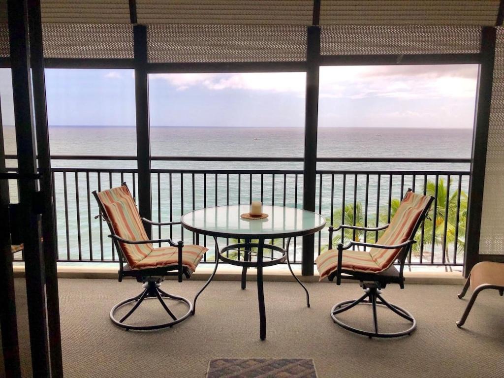 d'un balcon avec une table et des chaises donnant sur l'océan. dans l'établissement AMAZING OCEAN VIEW - Kona Alii Condo KA606, à Kailua-Kona