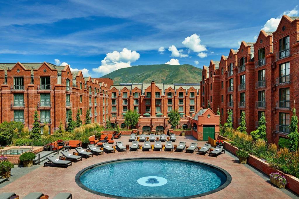 um pátio de hotel com piscina, cadeiras e edifícios em St. Regis Aspen Resort em Aspen