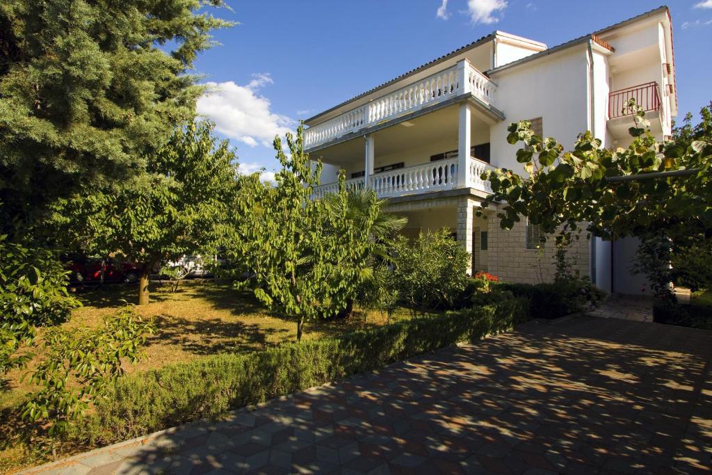 a large white house with a pathway in front of it at Milka Apartments in Njivice