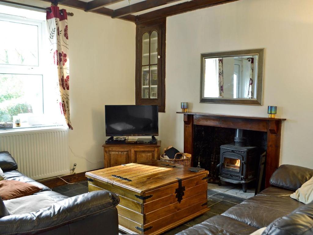 a living room with a fireplace and a tv at Holly Cottage in Ystalyfera