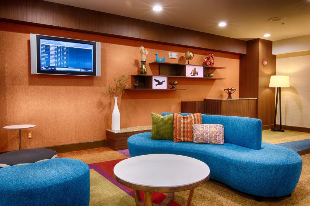 a living room with a blue couch and a tv at Fairfield Inn & Suites Jacksonville Airport in Jacksonville
