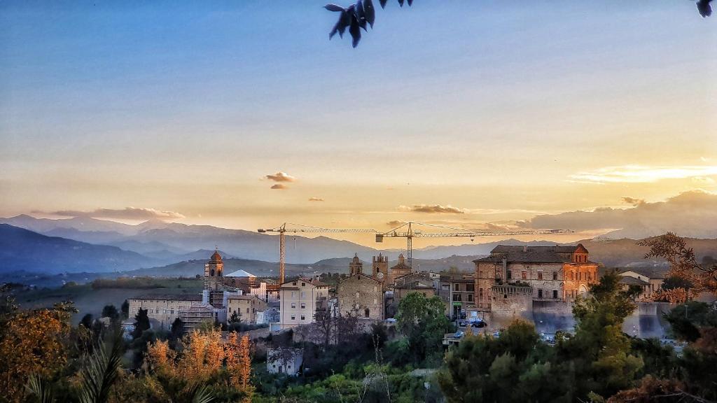 un paisaje urbano de una ciudad al atardecer con grúas en Chiocciola, en Offida