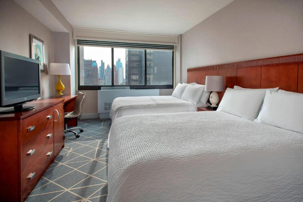 a hotel room with two beds and a flat screen tv at Courtyard by Marriott New York Manhattan/ Fifth Avenue in New York