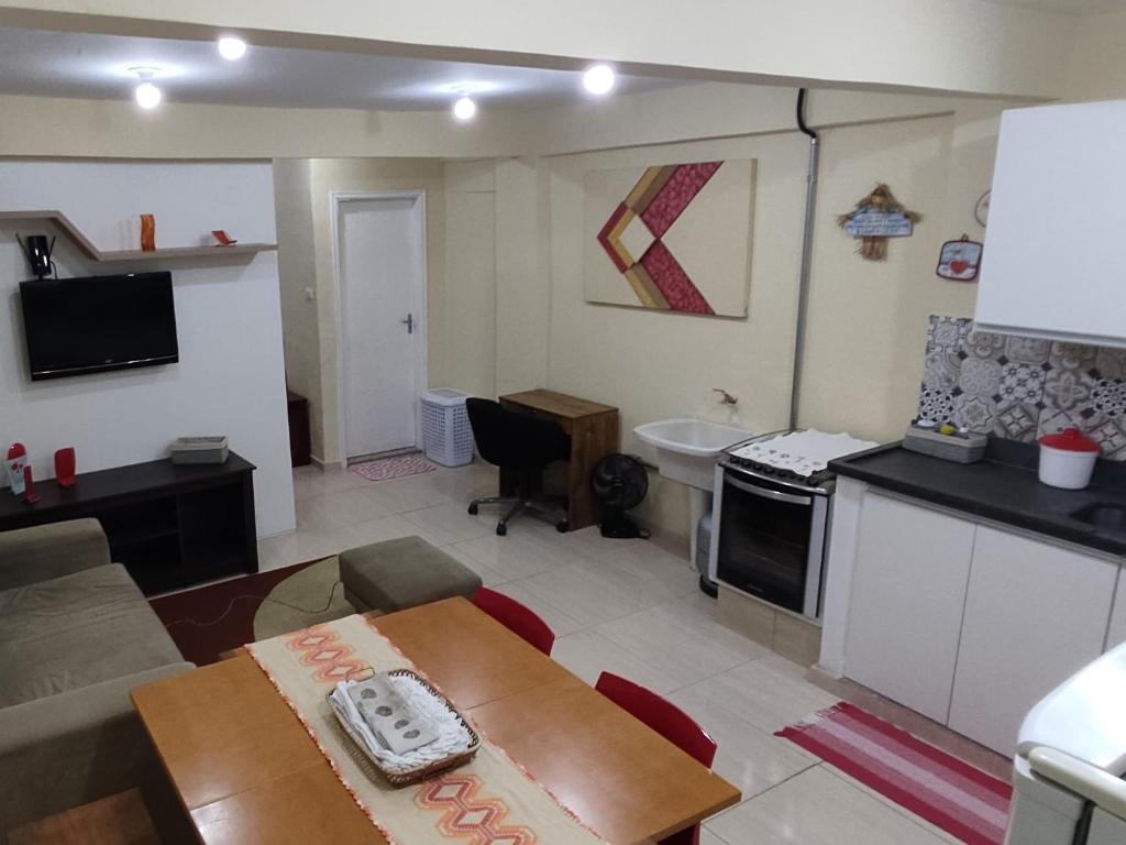 a kitchen and a living room with a table in a room at Estúdio Mobiliado em Poços in Poços de Caldas