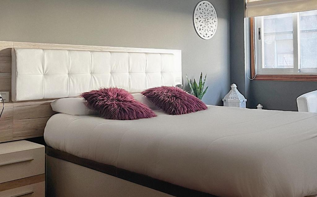 1 dormitorio con cama blanca y almohadas rosas en APARTAMENTO TORRE DE HÉRCULES A CORUÑA con GARAJE en A Coruña