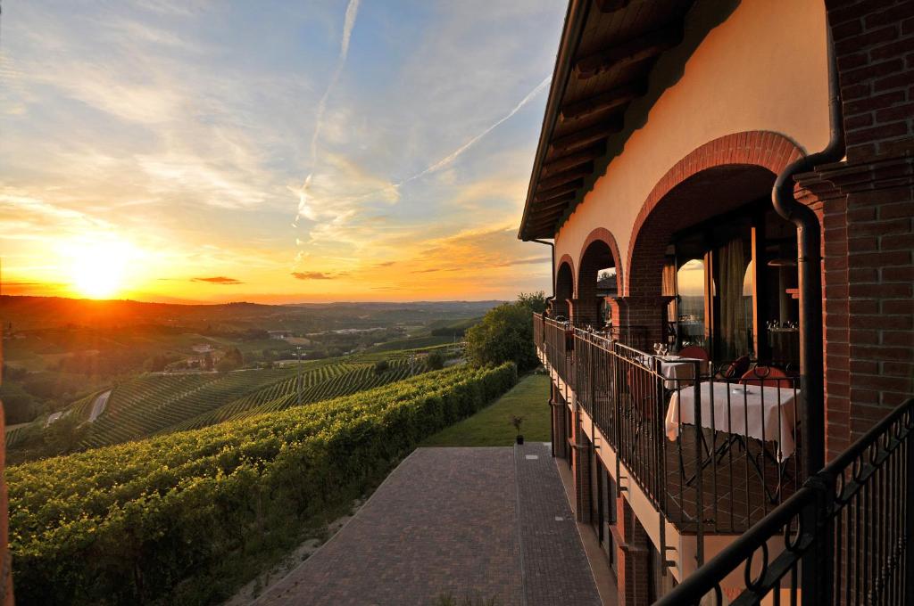 a building with a balcony with a sunset in the background at Tota Virginia Antico Podere in Serralunga d'Alba