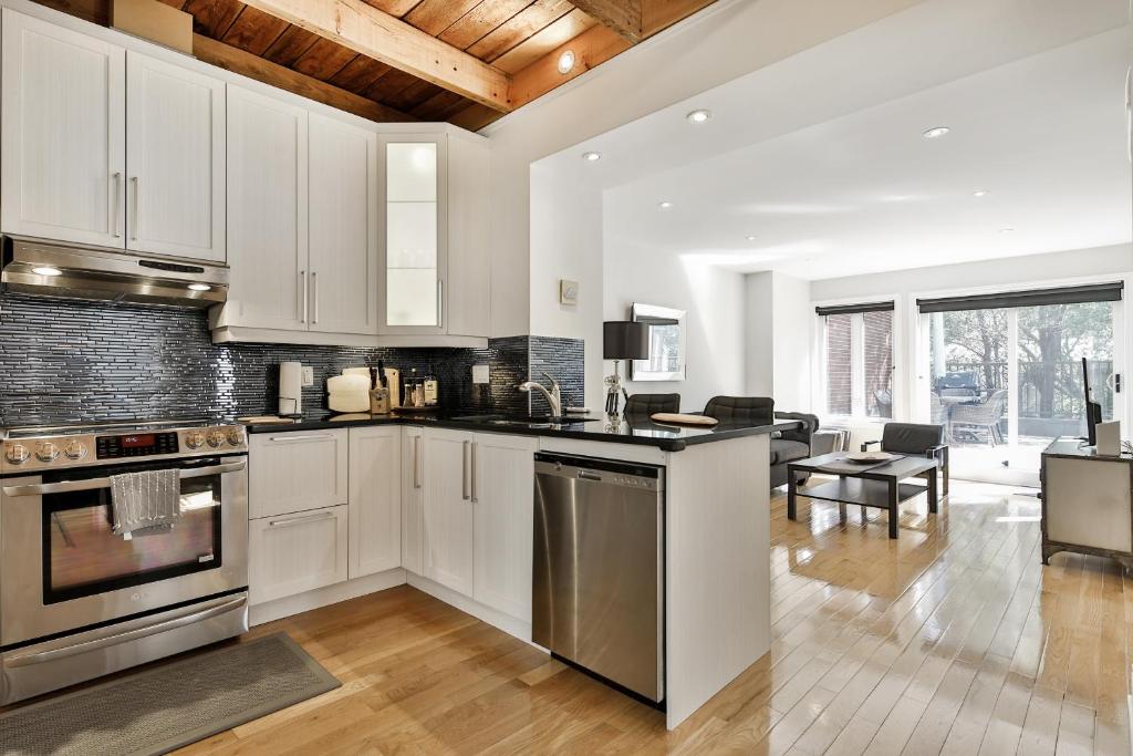 a kitchen with white cabinets and a living room at STUNNING condos on ST Denis in Montréal