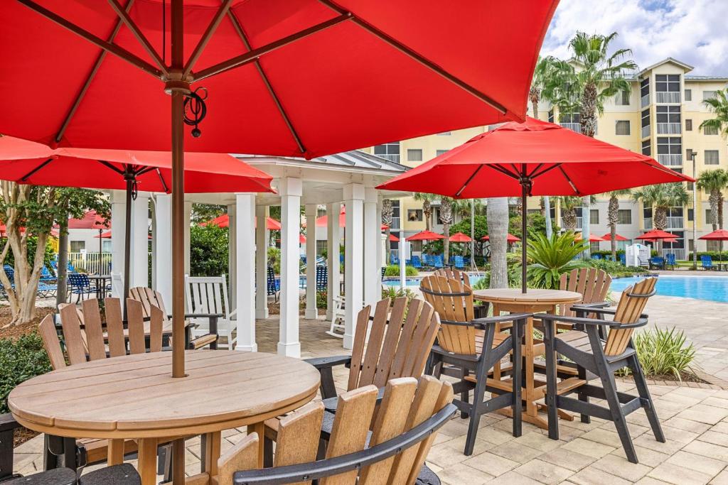 a patio with tables and chairs with red umbrellas at Marriott&#39;s Legends Edge at Bay Point in Panama City Beach