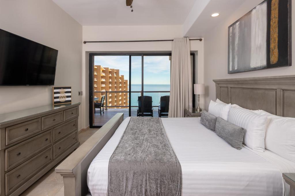 een slaapkamer met een groot bed en een televisie bij Luxury Oceanview Condo - Las Palomas - Pool, Golf, Sandy Beach ! in Puerto Peñasco