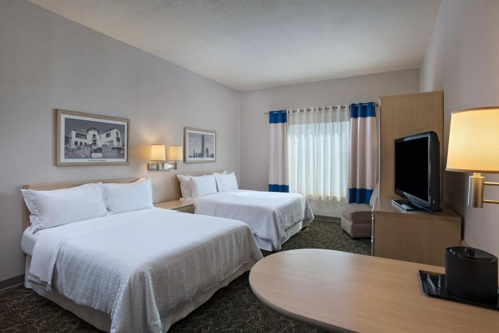 a hotel room with two beds and a flat screen tv at Four Points by Sheraton Galerias Monterrey in Monterrey