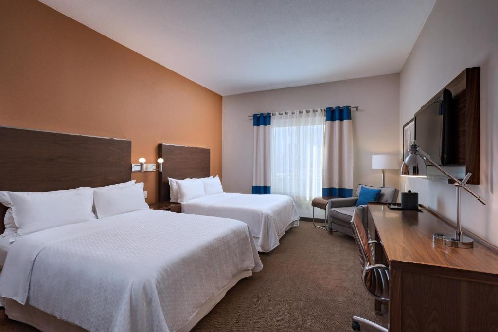 a hotel room with two beds and a television at Four Points by Sheraton Galerias Monterrey in Monterrey
