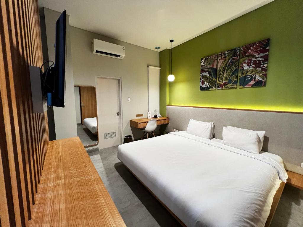 CASA CALMA HOTEL في جاكرتا: غرفة نوم بسرير ابيض وجدار اخضر