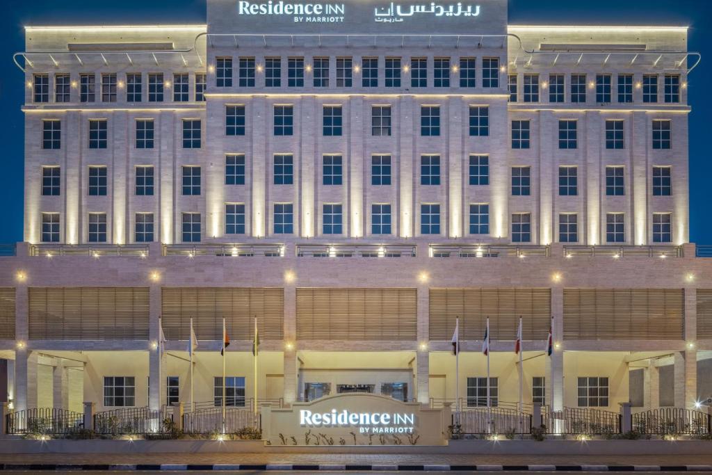 a large white building with flags in front of it at Residence Inn by Marriott Dammam in Dammam