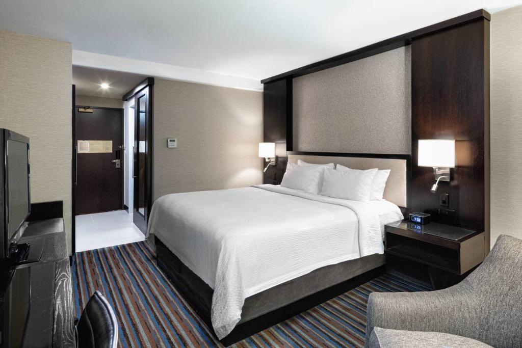 a hotel room with a large bed and a chair at Courtyard New York Manhattan/Times Square in New York