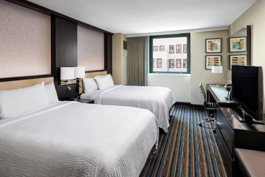 a hotel room with two beds and a flat screen tv at Courtyard New York Manhattan/Times Square in New York