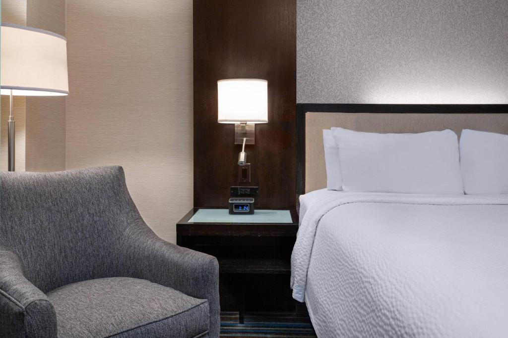 a bedroom with a bed and a chair and a lamp at Courtyard New York Manhattan/Times Square in New York