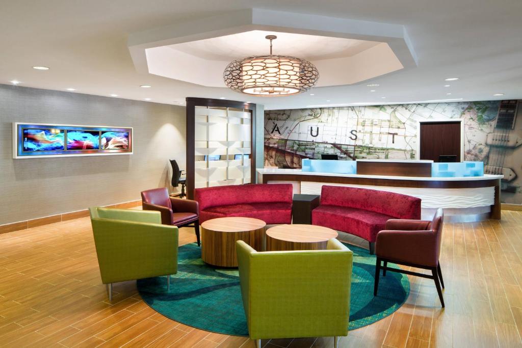 a lobby with red and green chairs and a bar at SpringHill Suites Austin South in Austin