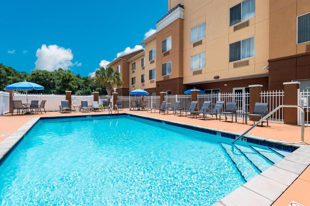 a swimming pool in front of a building with chairs and umbrellas at Fairfield Inn & Suites Marianna in Marianna