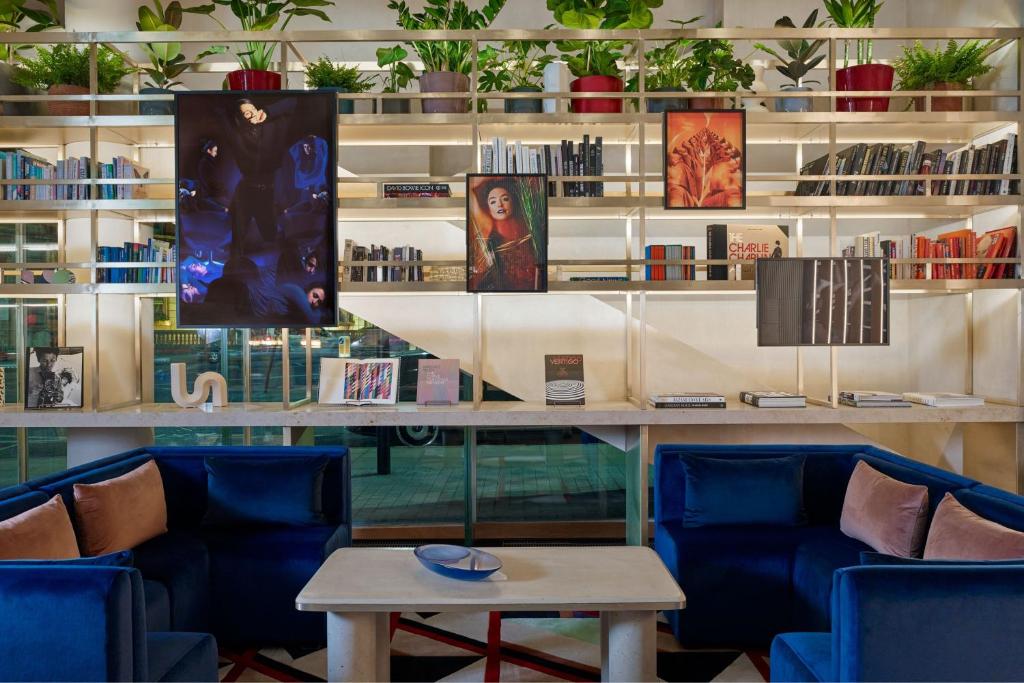 a room with blue chairs and a table and bookshelves at Montcalm East, Autograph Collection in London