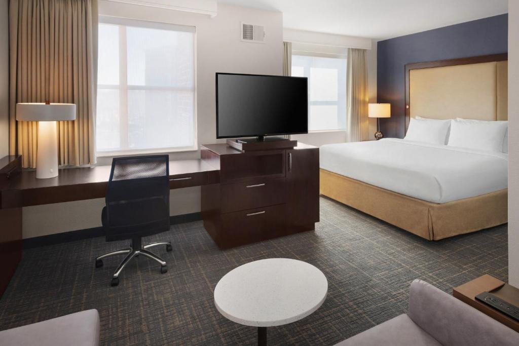 a hotel room with a bed and a desk with a television at Residence Inn by Marriott Fairfax City in Fairfax