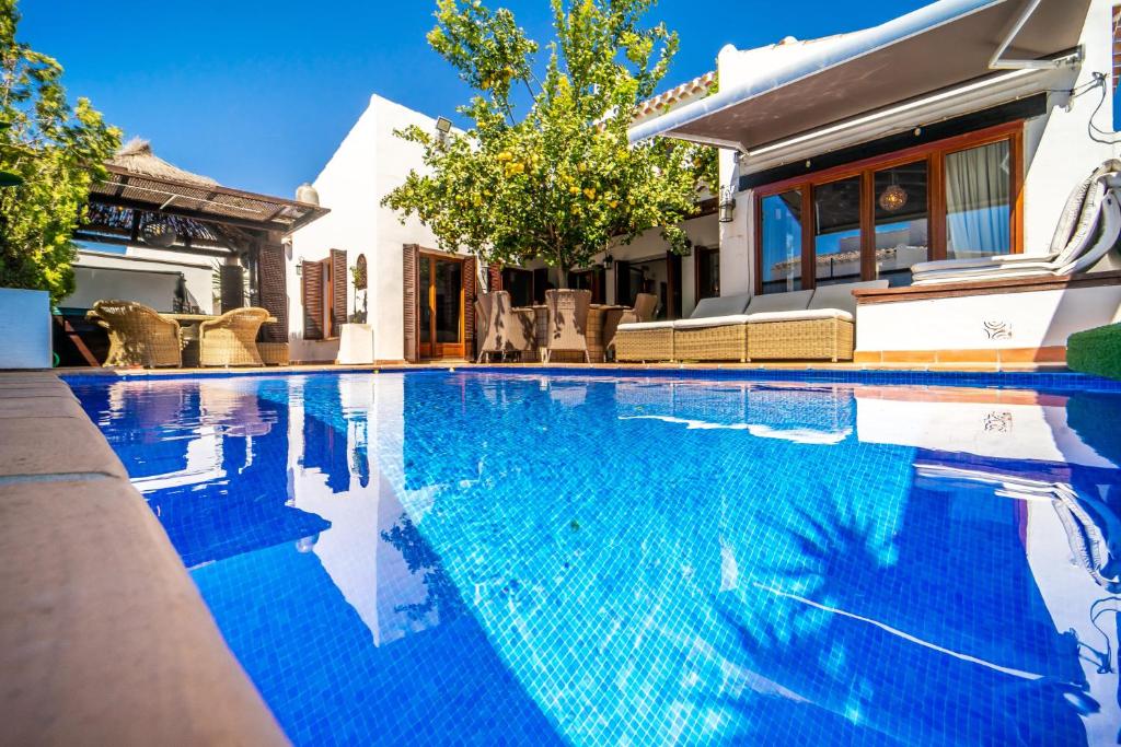 - une piscine d'eau bleue en face d'une maison dans l'établissement El Valle Golf Resort Villa private pool hot tub and sauna, à Baños y Mendigo