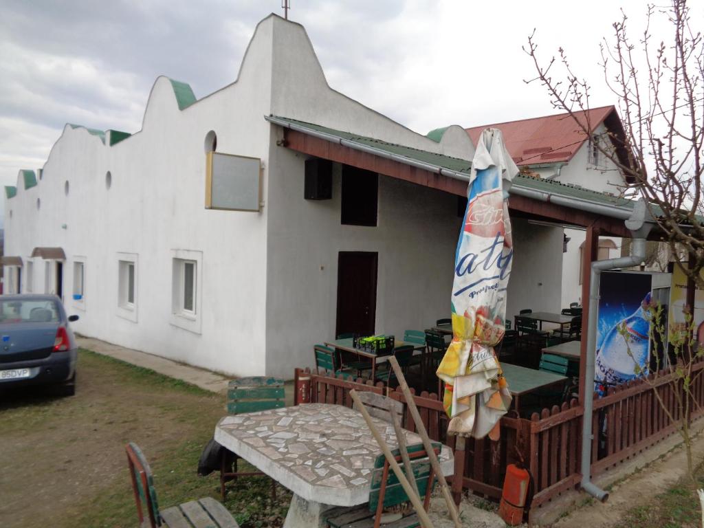 Casa blanca con mesa y sombrilla en Gasthaus Enduro Bica, en Caransebeş